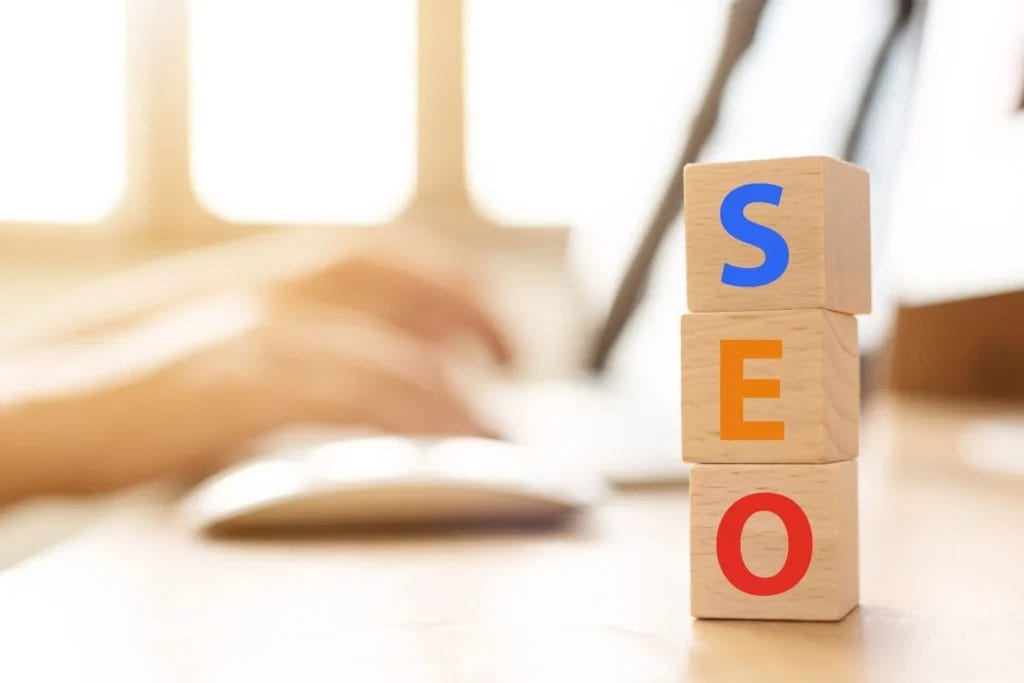 SEO blocks on a desk with typing hand.