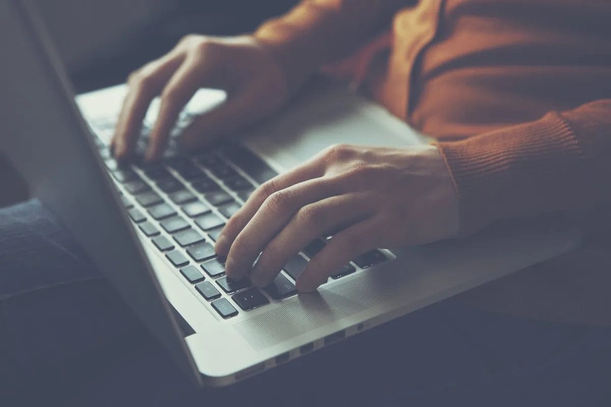 Person typing on laptop keyboard.