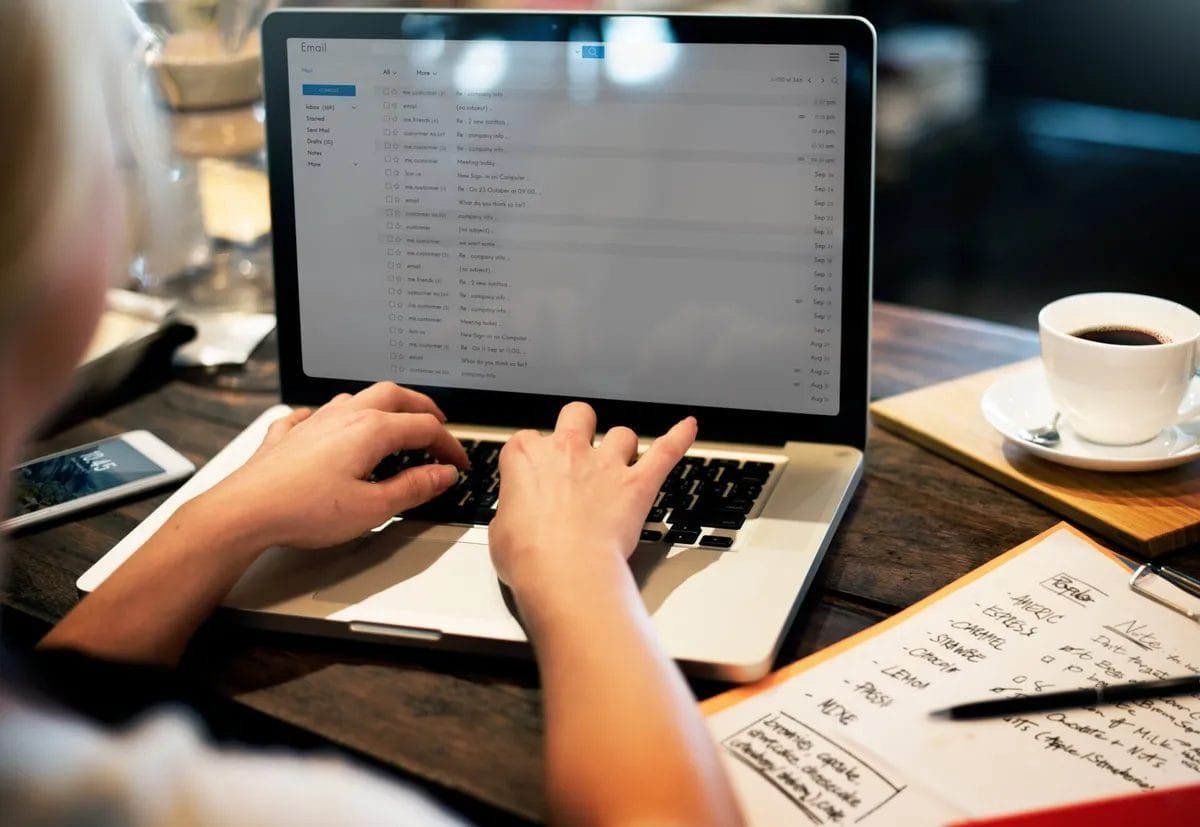 Person typing on laptop with coffee nearby.