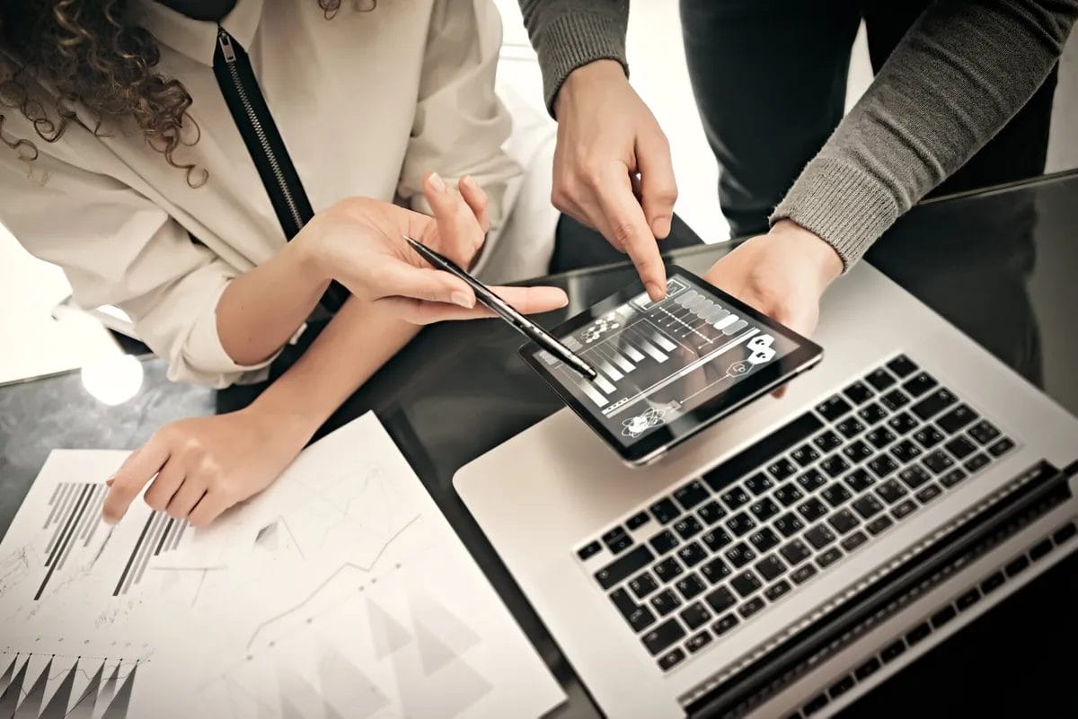 People analyzing charts on tablet and laptop together