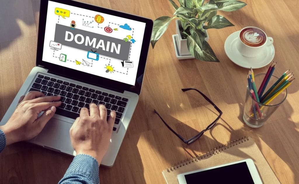Person researching domain on laptop with coffee nearby.