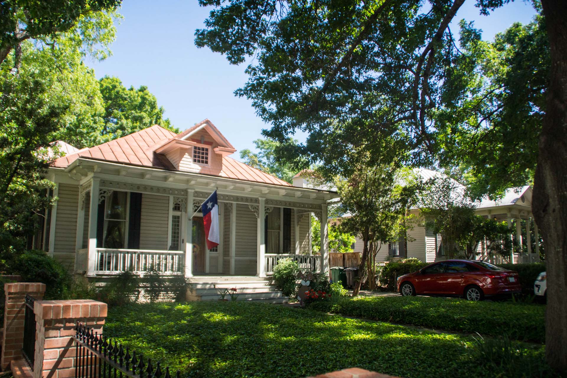Charming house with Texas flag and lush garden.